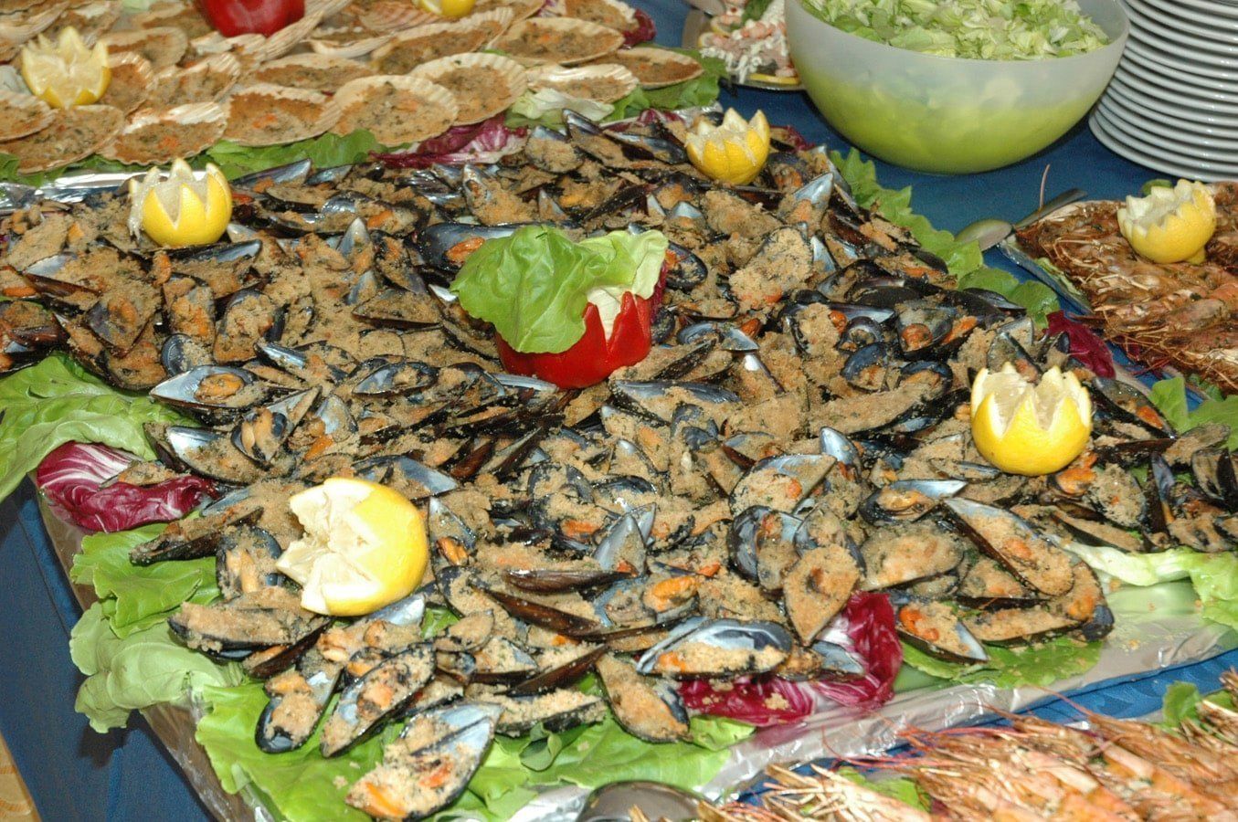 Una bandeja de mariscos con mejillones, camarones y otros mariscos, decorada con rodajas de limón y lechuga.