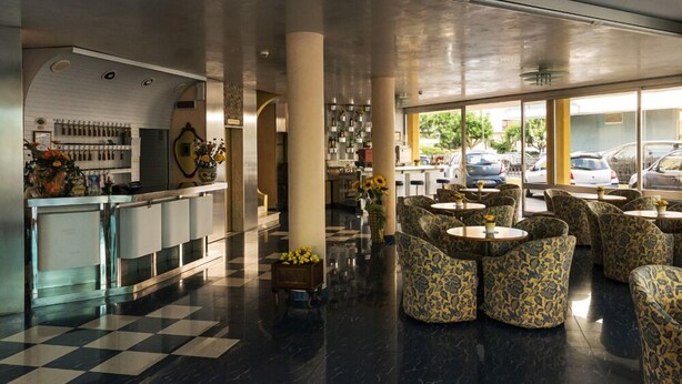 A hotel lobby with a checkered floor, a bar area, and seating with patterned upholstery. - Hotel Fabius (Bellaria-Igea Marina)
