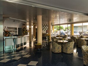 Een hotel lobby met een geruit vloerkleed, een bar en zitplaatsen met een patroon.