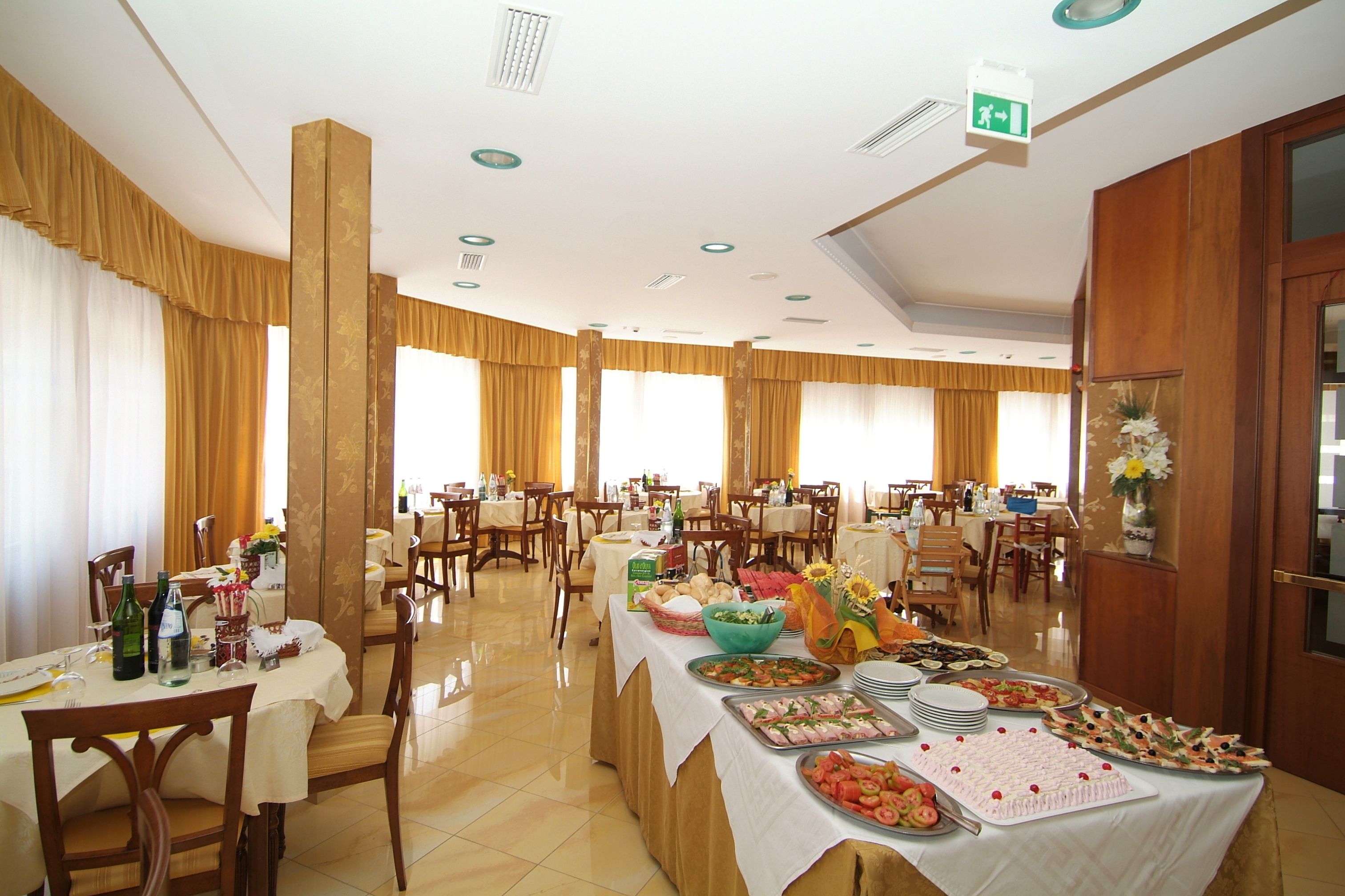 A spacious dining area with multiple tables, chairs, and a buffet setup.