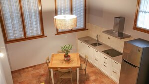 A compact kitchen with a dining area, a refrigerator, and a hanging light fixture.