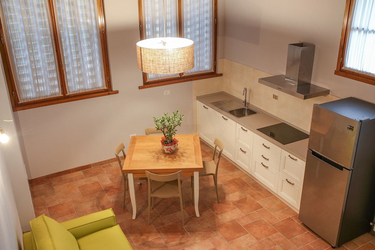 Una cocina compacta con comedor, refrigerador y una lámpara colgante.