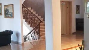 Un hall d’entrée spacieux, doté d’un parquet en bois poli, d’un escalier avec une rampe en métal et d’une porte donnant sur une autre pièce.