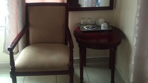 A room with a wooden chair, a small table with a tray, and a mirror on the wall. - Warm Hands Hotel (Kanye)