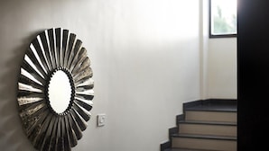 A modern interior with a unique wall-mounted mirror and a staircase. - Purple Cloud Hotel (Bengaluru)