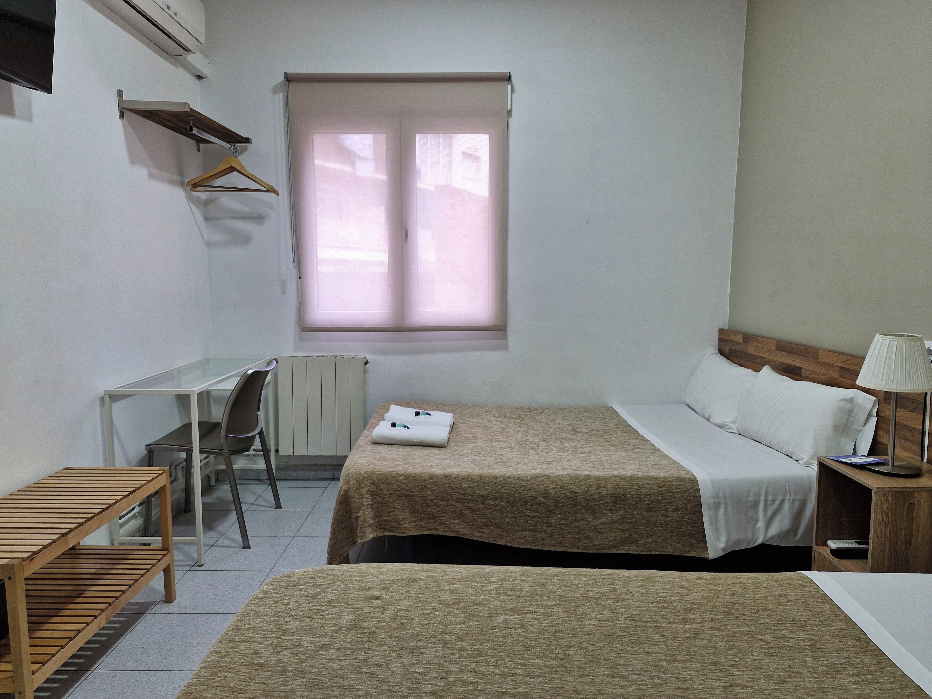 Een kleine, schone kamer met een bed, een bureau en een stoel.