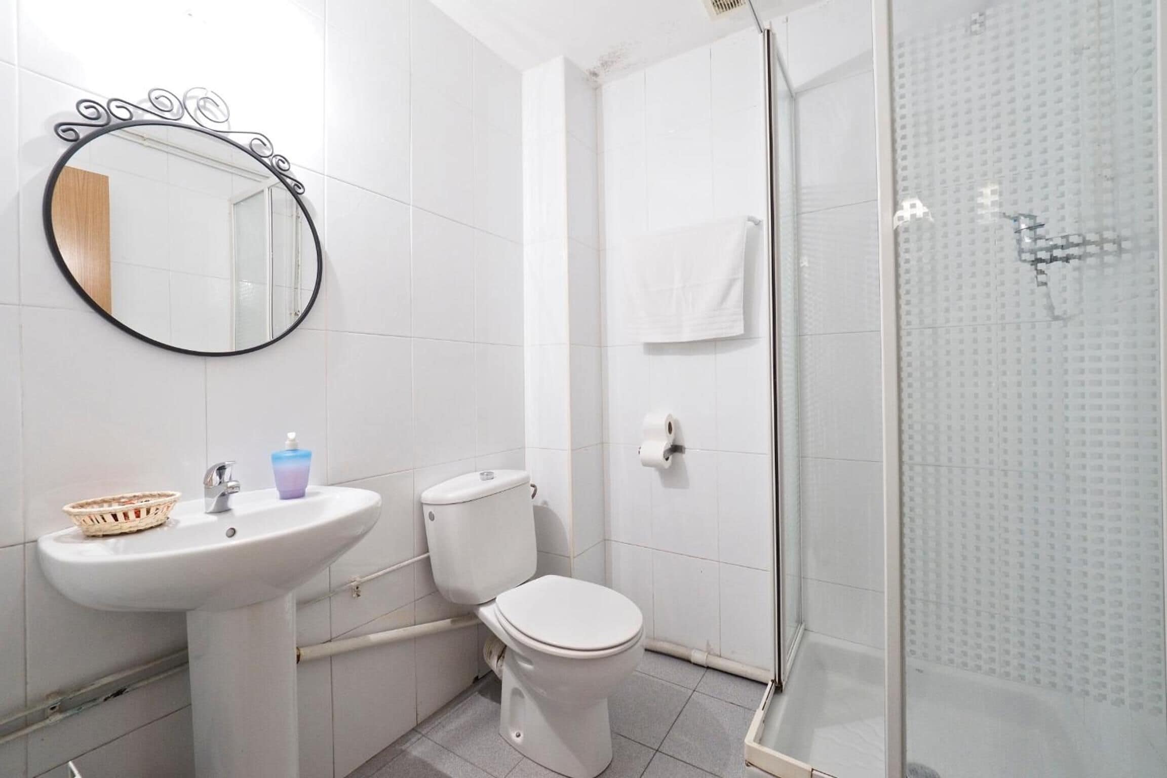 Un baño con lavamanos blanco, inodoro y cabina de ducha de vidrio.