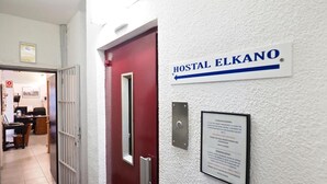 A hallway with a red door labeled "HOSTAL ELKANO" and a sign indicating the hostel's name. - Hostal Elkano (Barcelona)