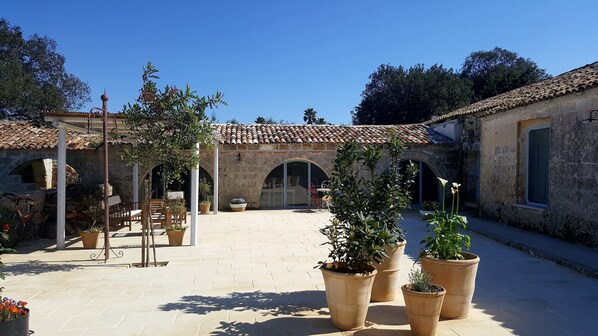 Un patio con paredes de piedra, arcos y plantas en macetas.