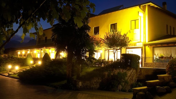 A two-story building with a yellow facade, a balcony with a railing, and a well-lit entrance. - Hotel Merloni (Grandola ed Uniti)