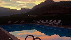 A swimming pool with lounge chairs and mountains in the background. - Hotel Merloni (Grandola ed Uniti)