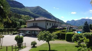 A large house with a paved driveway and a small tree in the foreground. - Hotel Merloni (Grandola ed Uniti)