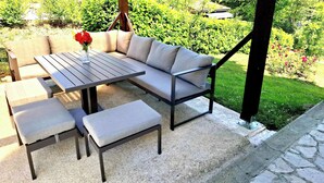 Eine Außenpatio mit einer grauen Couch, einem Holztisch und passenden Bänken.