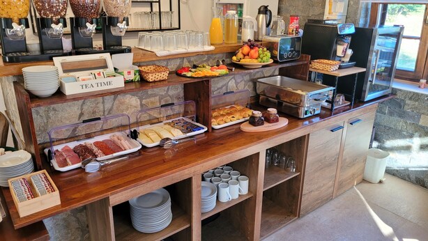 Ein reichhaltiges Frühstücksbuffet mit verschiedenen Speisen, einer Kaffeemaschine und einem Saftspender.