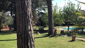 A backyard with a swimming pool, a dog, and a tree. - Villa al Piano (Lastra a Signa)