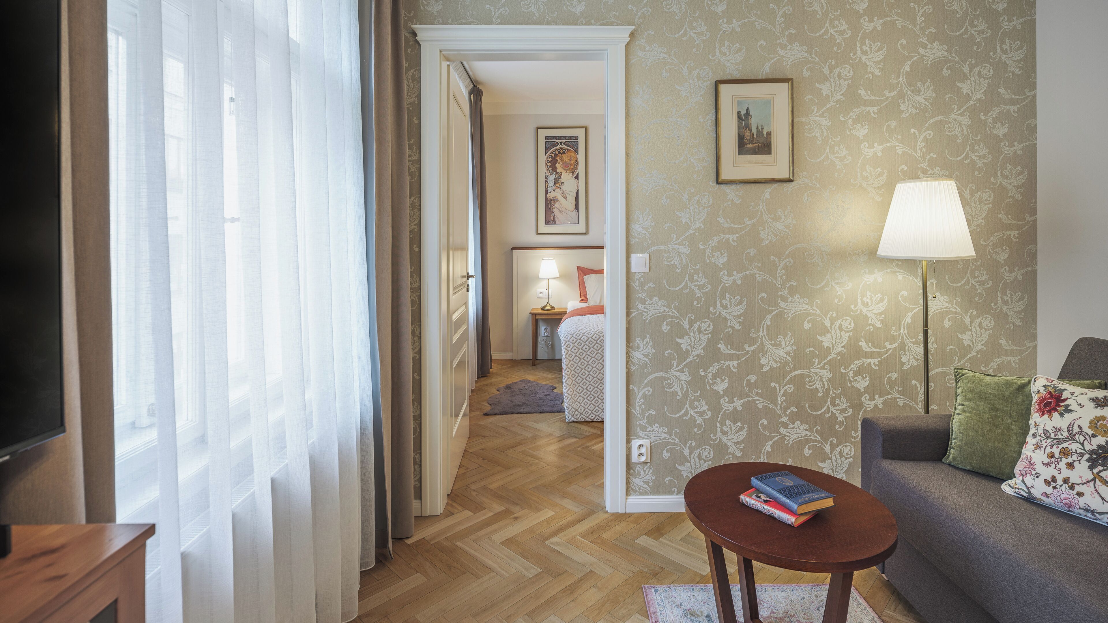 Una sala de estar con un sofá, una mesita con libros, una lámpara y un cuadro en la pared.