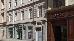 Un edificio de varios pisos con un estilo arquitectónico clásico, con ventanas amplias y una entrada a nivel de calle con un letrero.