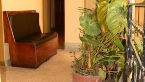 A hallway with a wooden bench, potted plants, and a metal gate. - New Swanga Guest House (Nairobi)