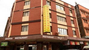 A multi-story building with a prominent yellow vertical sign for 'SWANGA RESTAURANT' on the facade. - New Swanga Guest House (Nairobi)