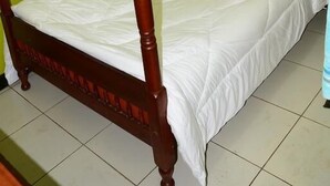 A single bed with a wooden frame and white bedding in a room with green walls and a window with a curtain. - New Swanga Guest House (Nairobi)