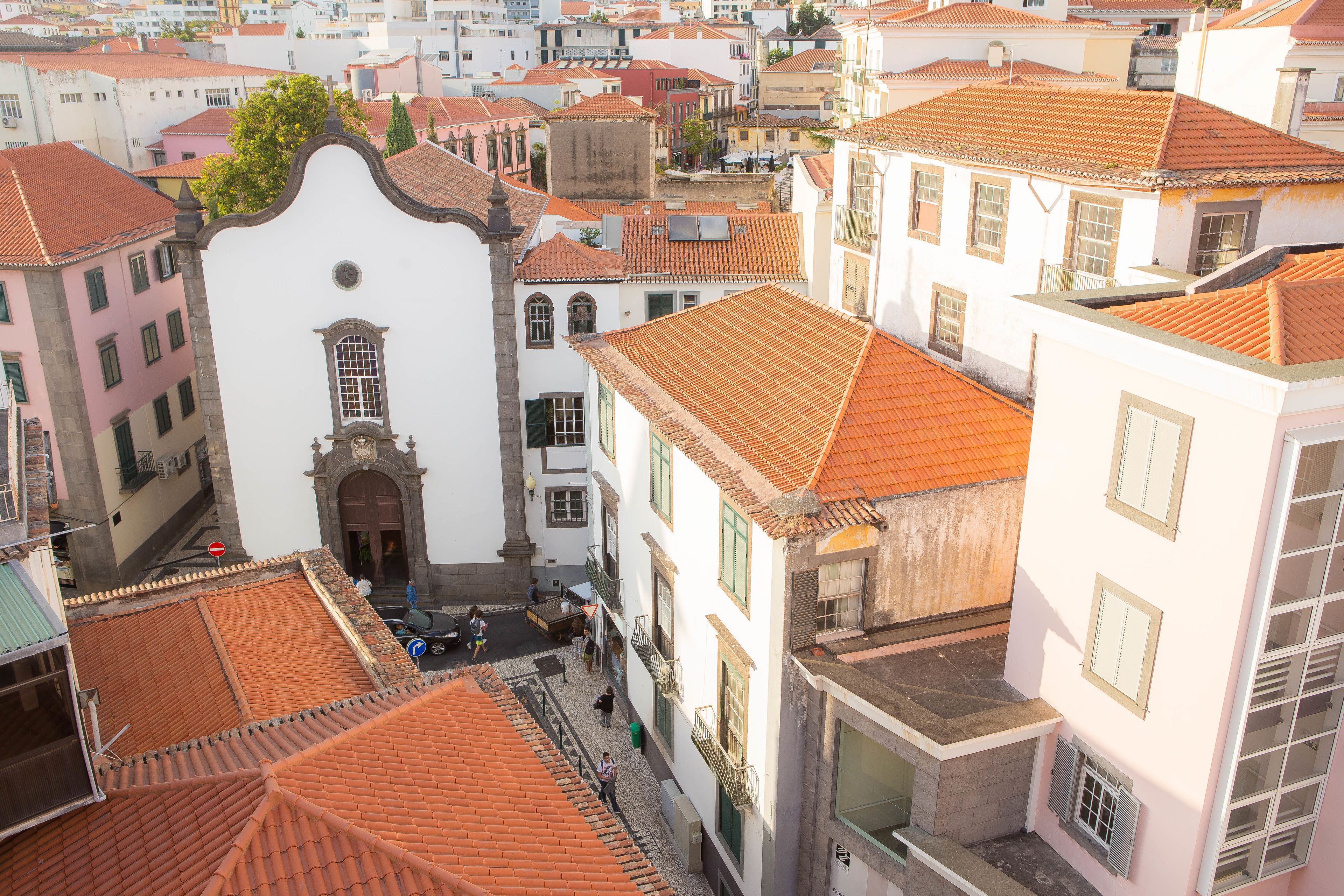 Un estrecho callejón con edificios de paredes blancas y tejados de tejas rojas, típico de un pueblo histórico europeo.