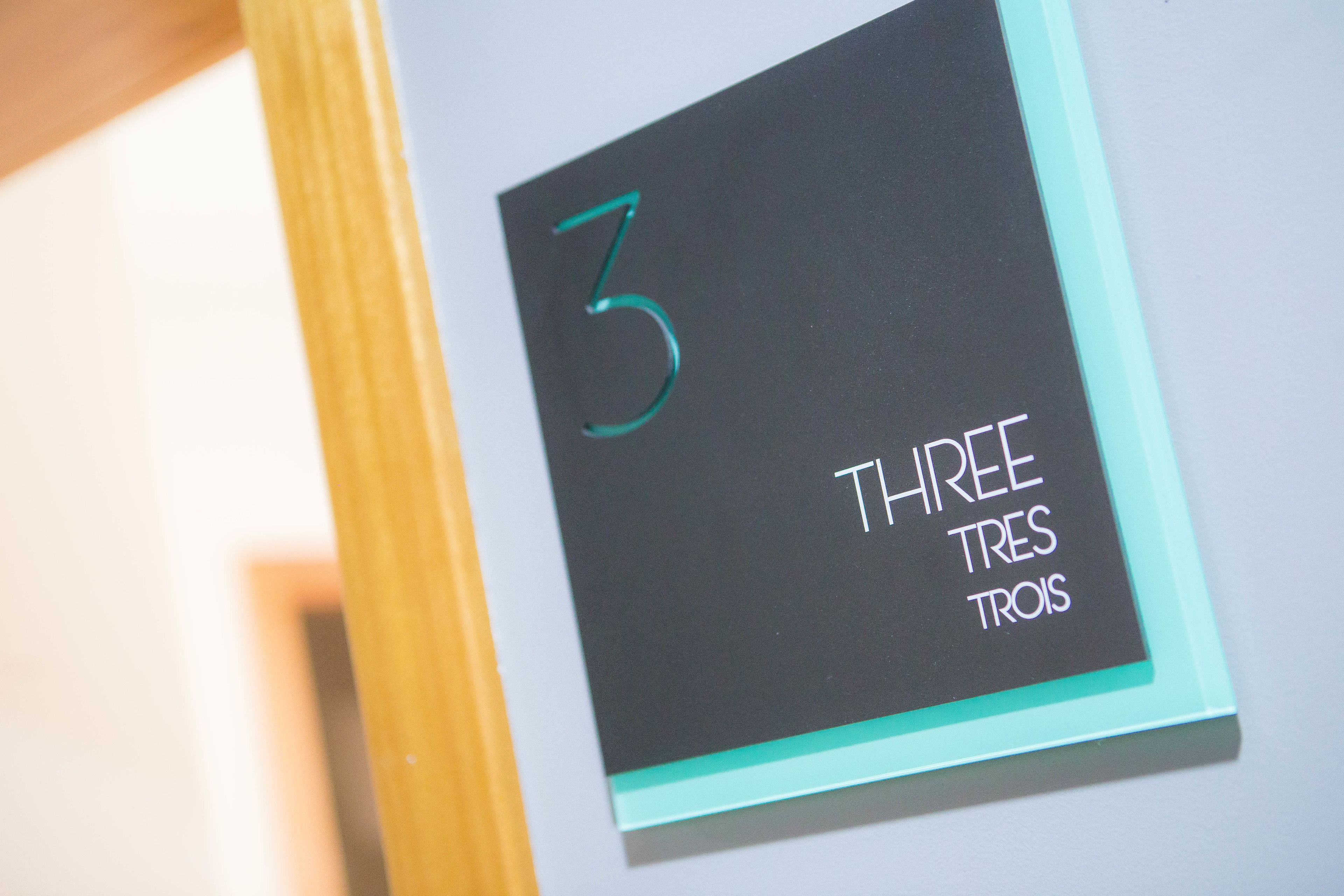 En skylt med siffran 3 och texten ”THREE” på flera språk.