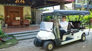 A golf cart parked in front of a building with a red roof and a wooden bench area. - Bali Paradise Heritage by Prabhu (Ungasan)
