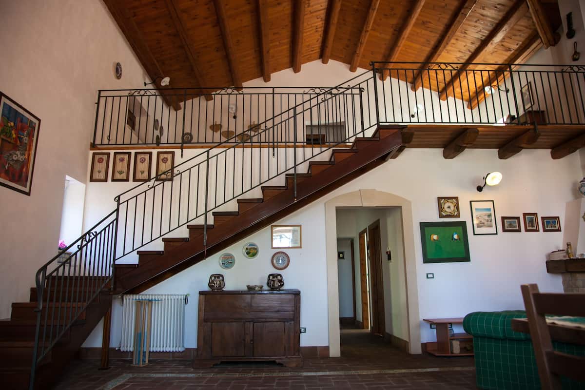 Un escalier en bois, doté d’une rampe, mène à un niveau supérieur. On peut apercevoir un radiateur sur le mur situé en contrebas de l’escalier.