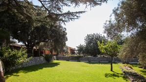 A well-maintained grassy lawn with stone walls and trees. - Agriturismo Borgo degli Ulivi (Palazzolo Acreide)