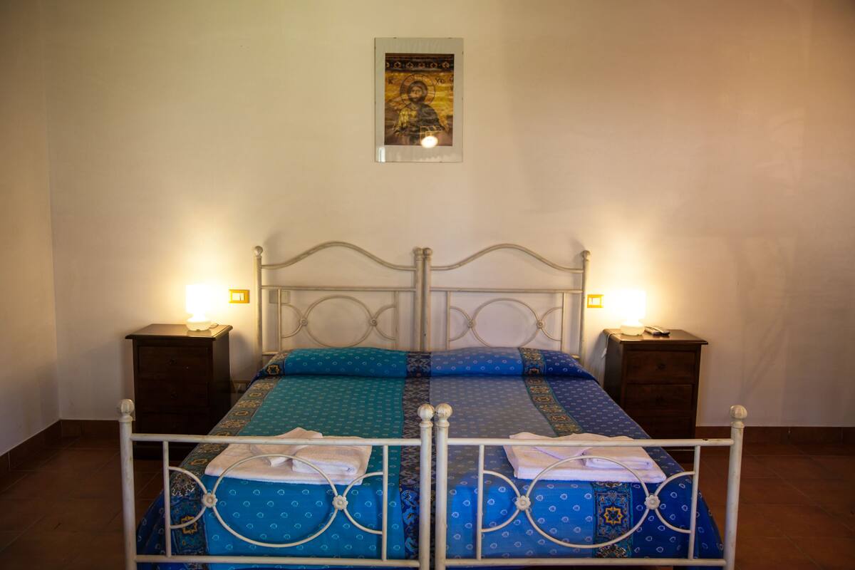 Un lit avec un cadre en métal, deux tables de chevet et un tableau accroché au mur.