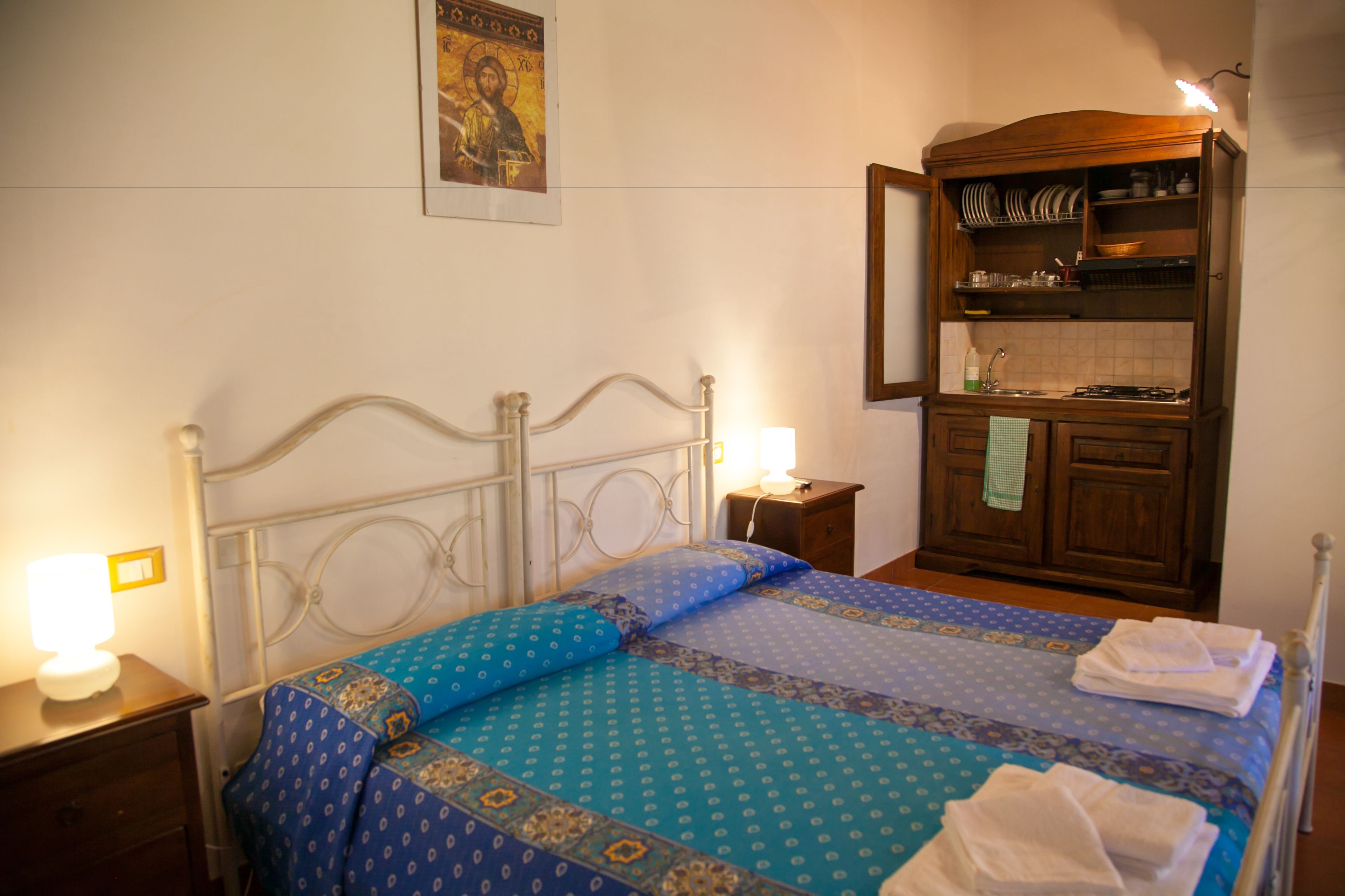 Une chambre à coucher comprenant un lit, des tables de chevet, une armoire en bois et un luminaire fixé au mur.