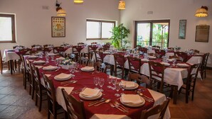 A restaurant with multiple tables set for dining, featuring red tablecloths and wooden chairs. - Agriturismo Borgo degli Ulivi (Palazzolo Acreide)