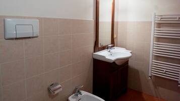 Ein Badezimmer mit Toilette, Bidet, Waschbecken und Handtuchhalter.