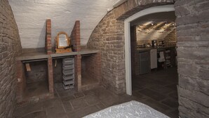 A bedroom with a bed, a mirror, and a brick fireplace. - The Priory Cellars Abbots Leigh (Bristol)