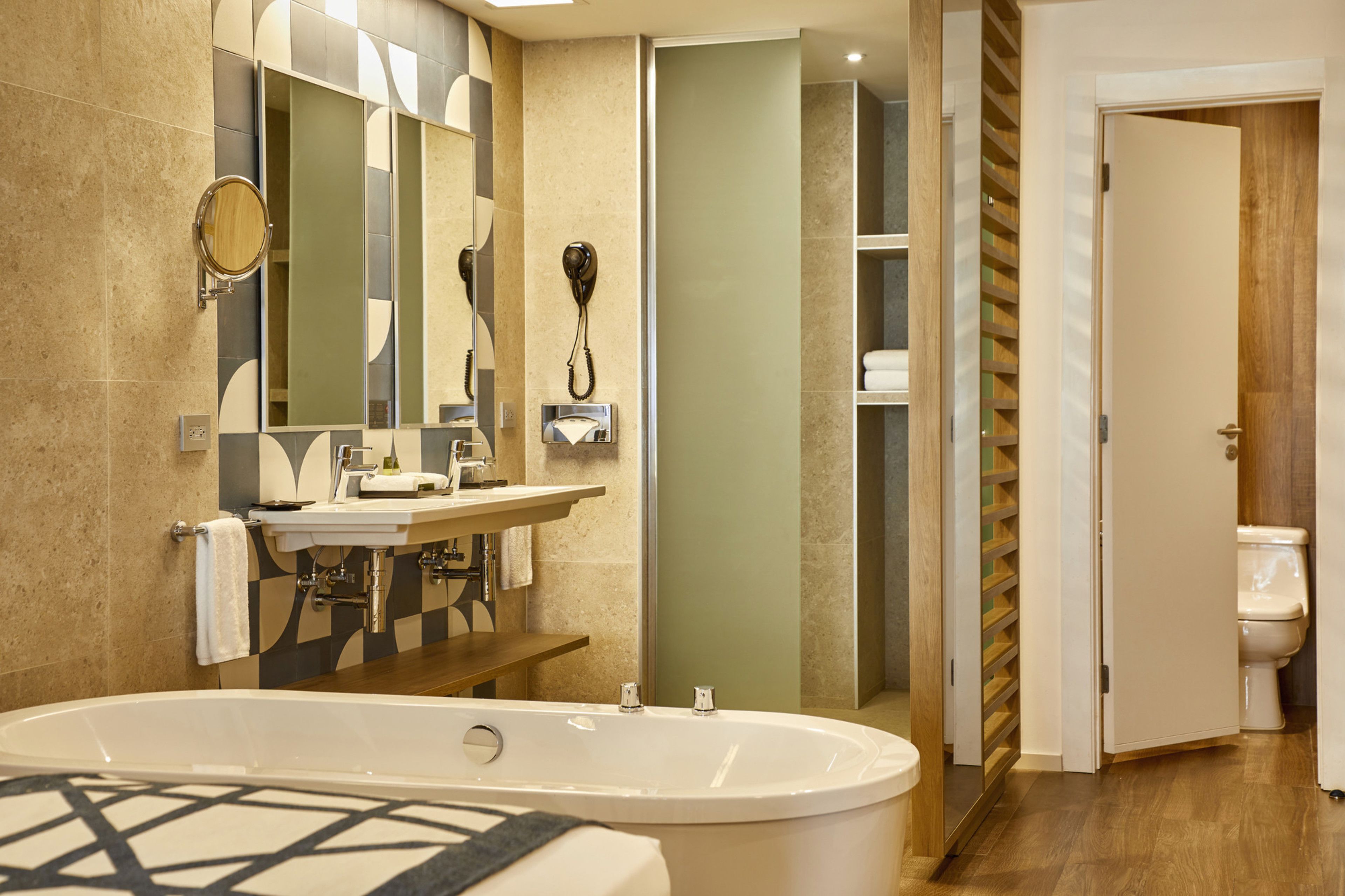 A modern bathroom with a large bathtub, a vanity with a mirror, and a toilet.