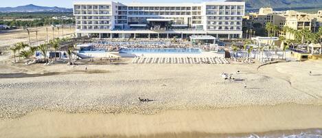 A beachfront hotel with multiple floors, a pool area, and a beach.