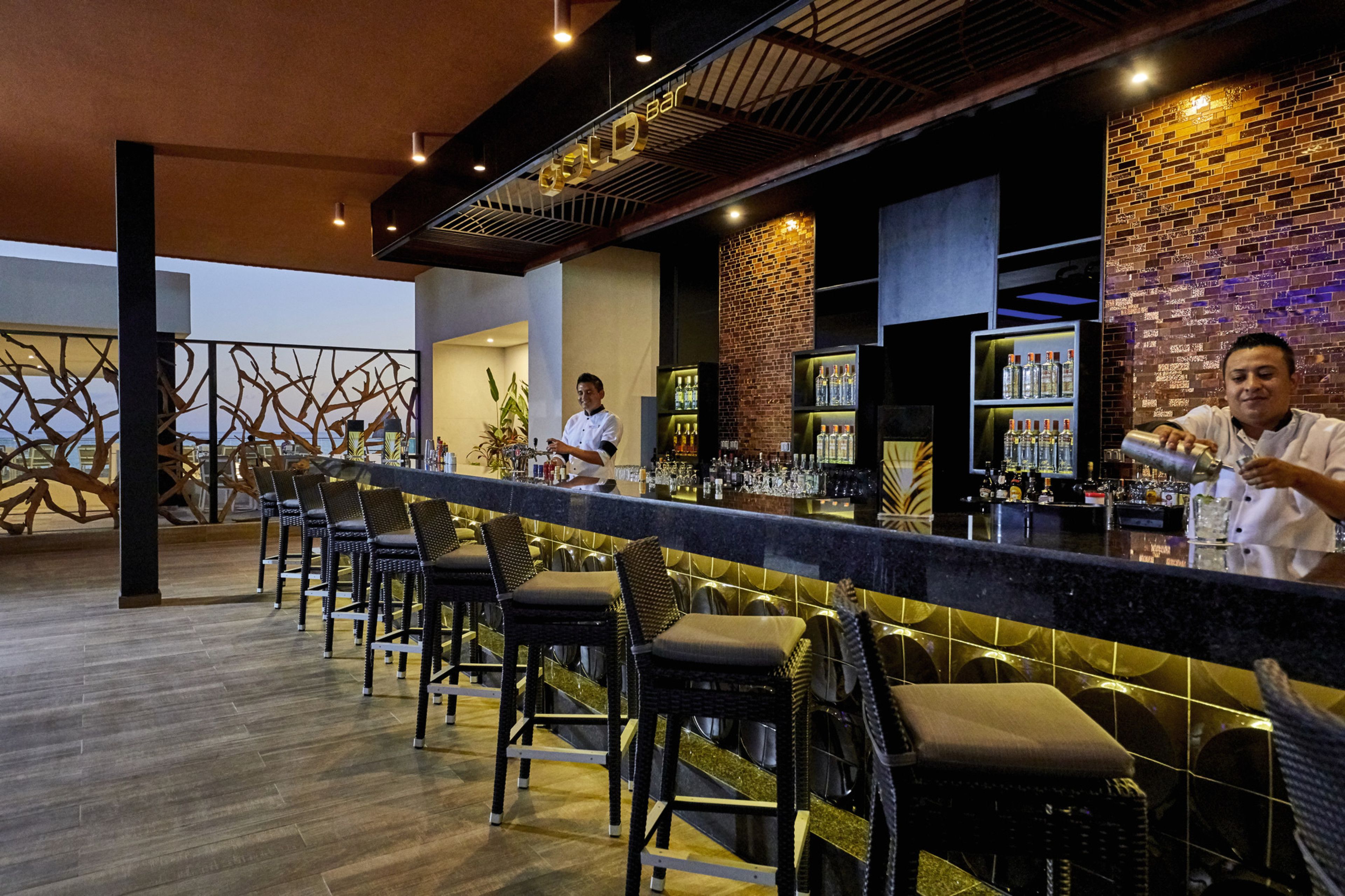 Zona de bar con mostrador, taburetes y un cantinero.