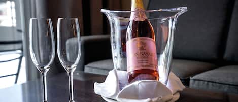 Una botella de vino rosado Mon-Basart en un decantador de vidrio transparente sobre una mesa con dos copas de vino vacías.