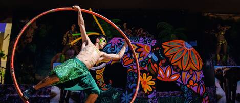 A performer in a green outfit manipulating a hula hoop.