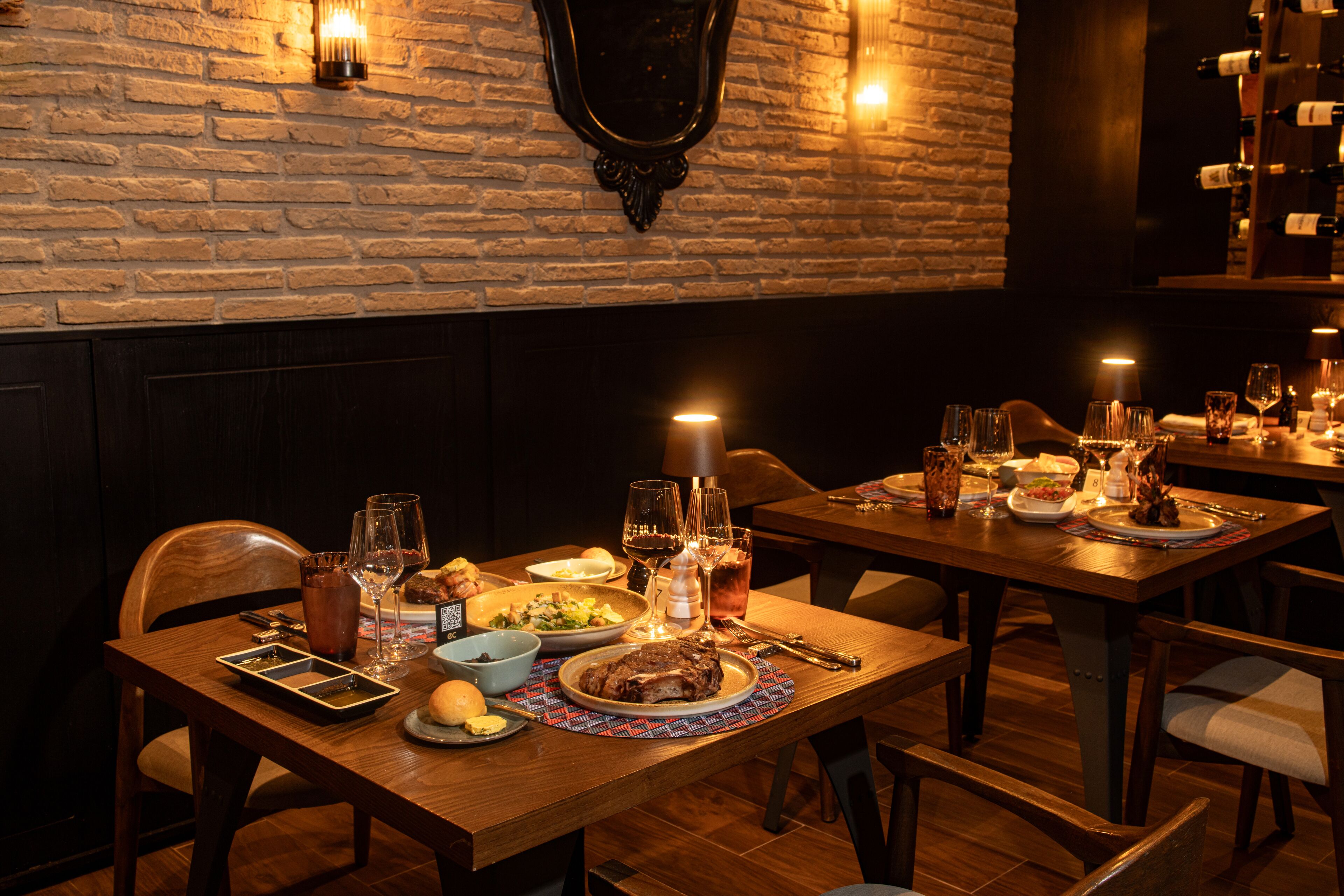 Een restaurant met bakstenen muren, houten tafels en een ruime keuze aan gerechten en dranken.