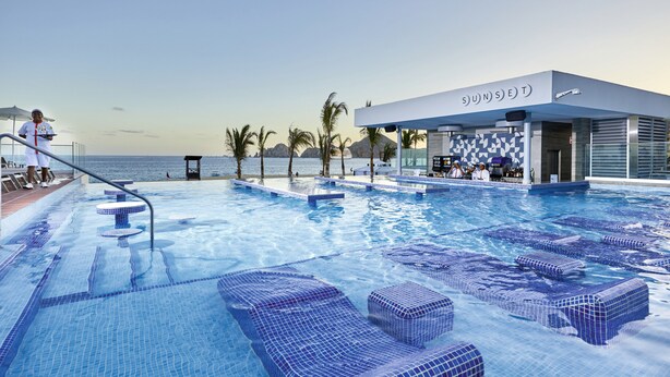 Una piscina amb gandules i una zona de bar anomenada "SUNSET".