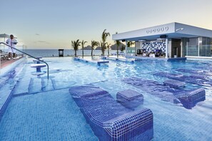 A swimming pool with lounge chairs and a bar area named "SUNSET". - Hotel Riu Palace Baja California - Adults Only - All Inclusive (Cabo San Lucas)