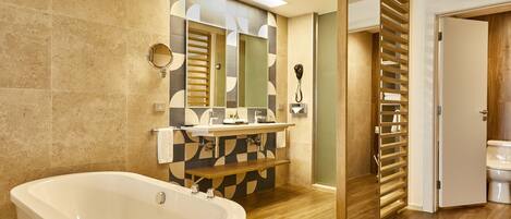 A modern bathroom with a freestanding bathtub, a vanity with a mirror, and a toilet with a wooden slatted door.
