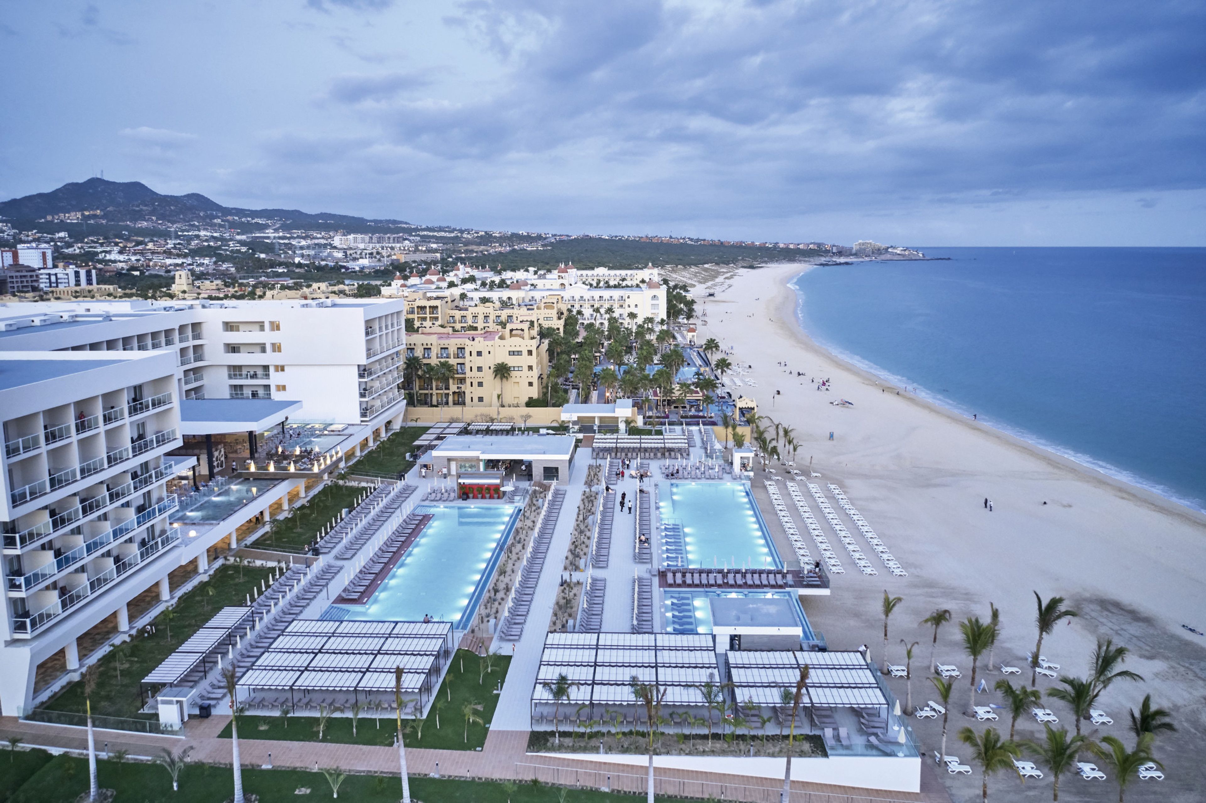Un resort con una amplia zona de piscina, acceso a la playa y vistas al océano.