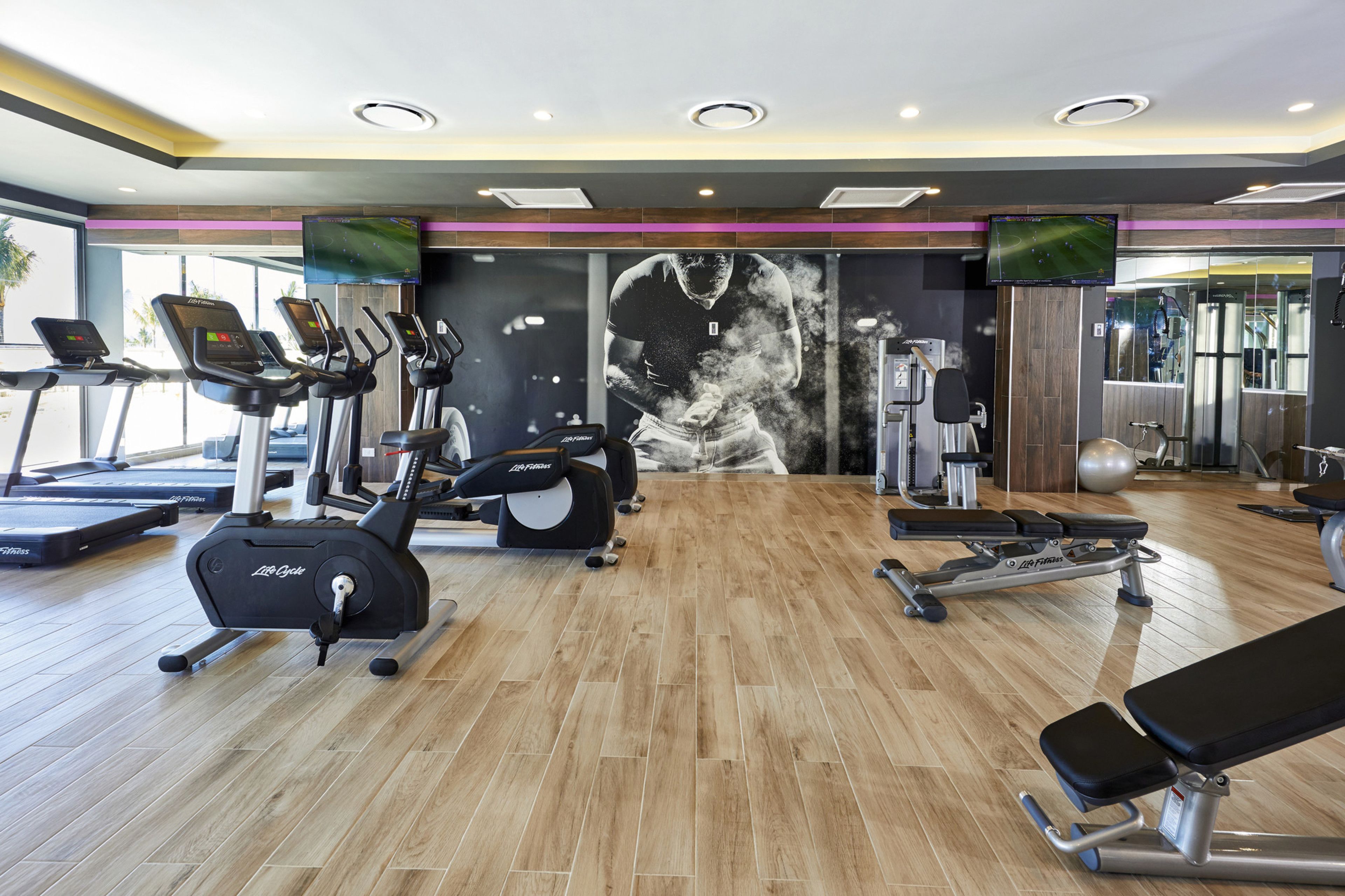 A modern gym with treadmills, elliptical machines, and weight equipment.