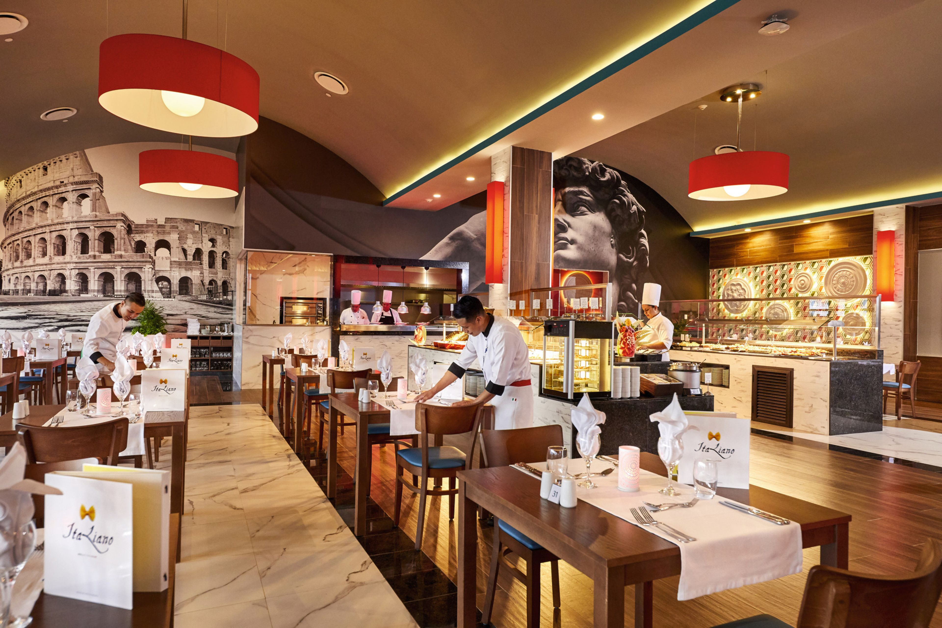 A restaurant with a large coliseum mural, modern pendant lighting, and a bar area with a chef preparing food.