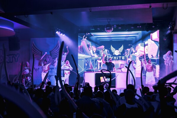 A concert stage with a band performing, a large audience, and a DJ booth.