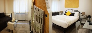 A hotel room with a bed, a small table with candles, a radiator, and a decorative wall piece. - Mirabilia Guest House (Rome)