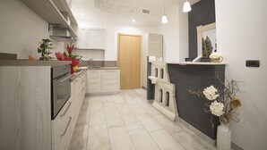 A modern kitchen with white cabinetry, a built-in oven, and a decorative island. - Mirabilia Guest House (Rome)