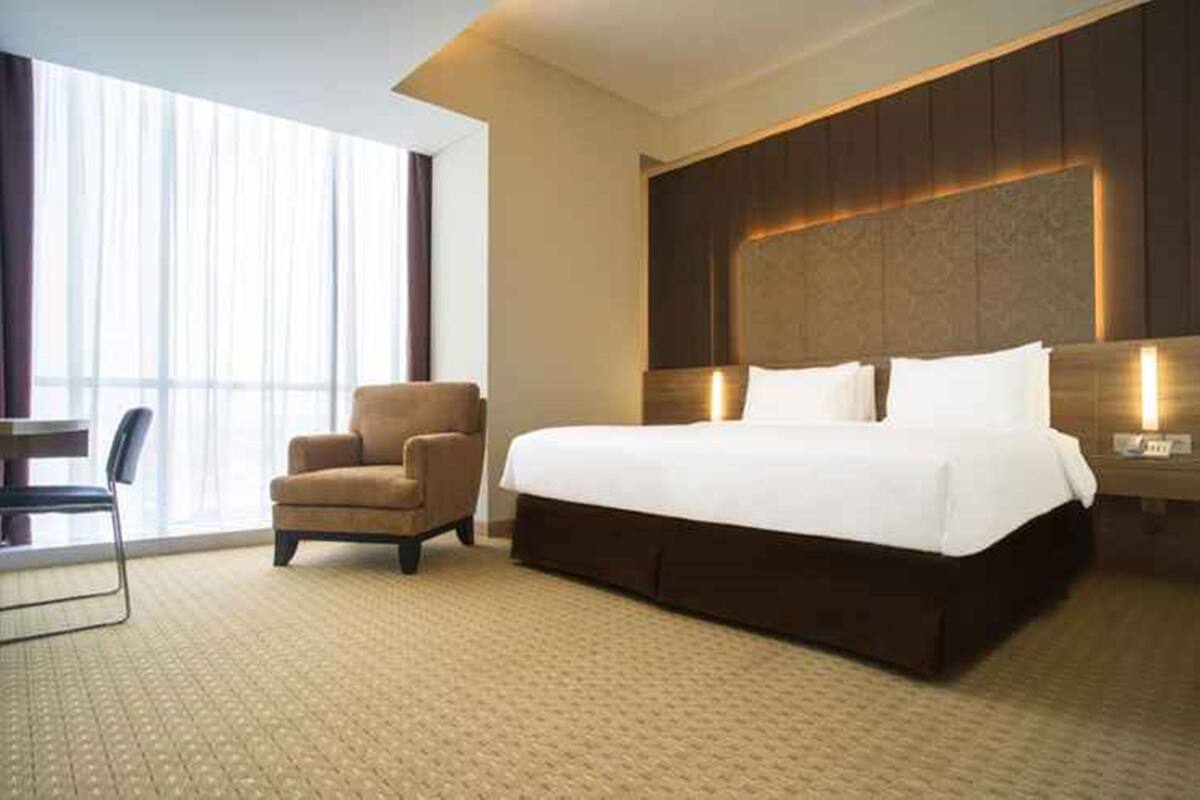 Une chambre d’hôtel avec un grand lit, une chaise et un bureau.